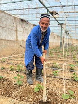 A person in a blue robe holding a stick in a greenhouse  AI-generated content may be incorrect.